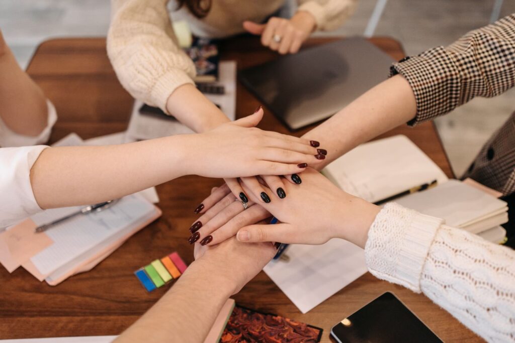 Crafting Captivating Headlines: Your awesome post title goes here Hands stacked in teamwork gesture over a table with office items symbolizing collaboration.