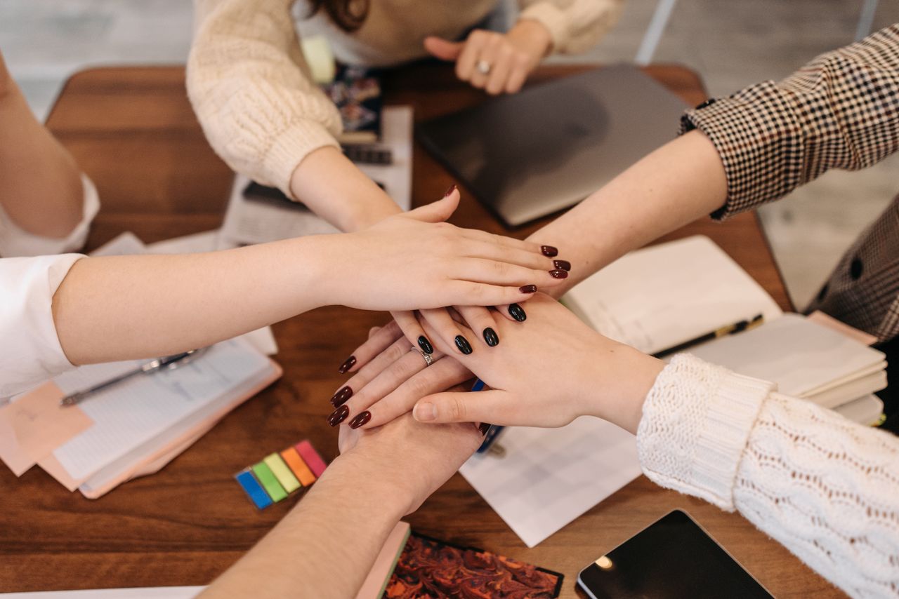 Crafting Captivating Headlines: Your awesome post title goes here Hands stacked in teamwork gesture over a table with office items symbolizing collaboration.